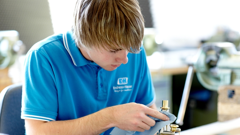 Apprentice polishing metal object.