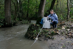 Eine Frau überwacht die Wasserqualität eines Flusses in einem Wald