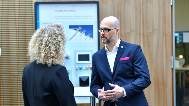 Mitarbeiter und Kunde diskutieren bei einem Seminar vor einem Messemodell