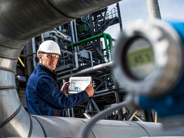 Ingenieur, der an einem industriellen Tablet in einer Raffinerie arbeitet.