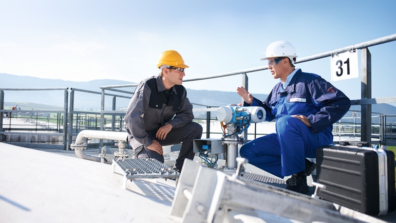 Kunde und Endress+Hauser Ingenieur disktutieren auf dem Dack eines Flüssigkeitstanks.